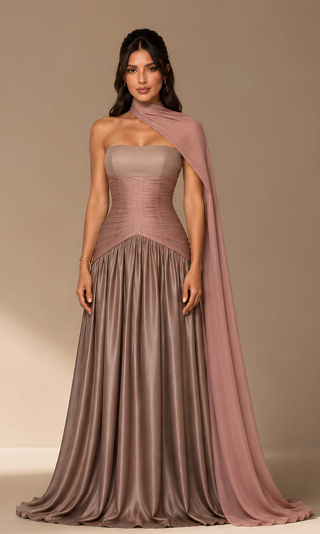 A model wearing the limited-edition Joie Couture gown in mauve, with a ruched bodice and a draped chiffon sash over one shoulder, photographed against a pale studio ground