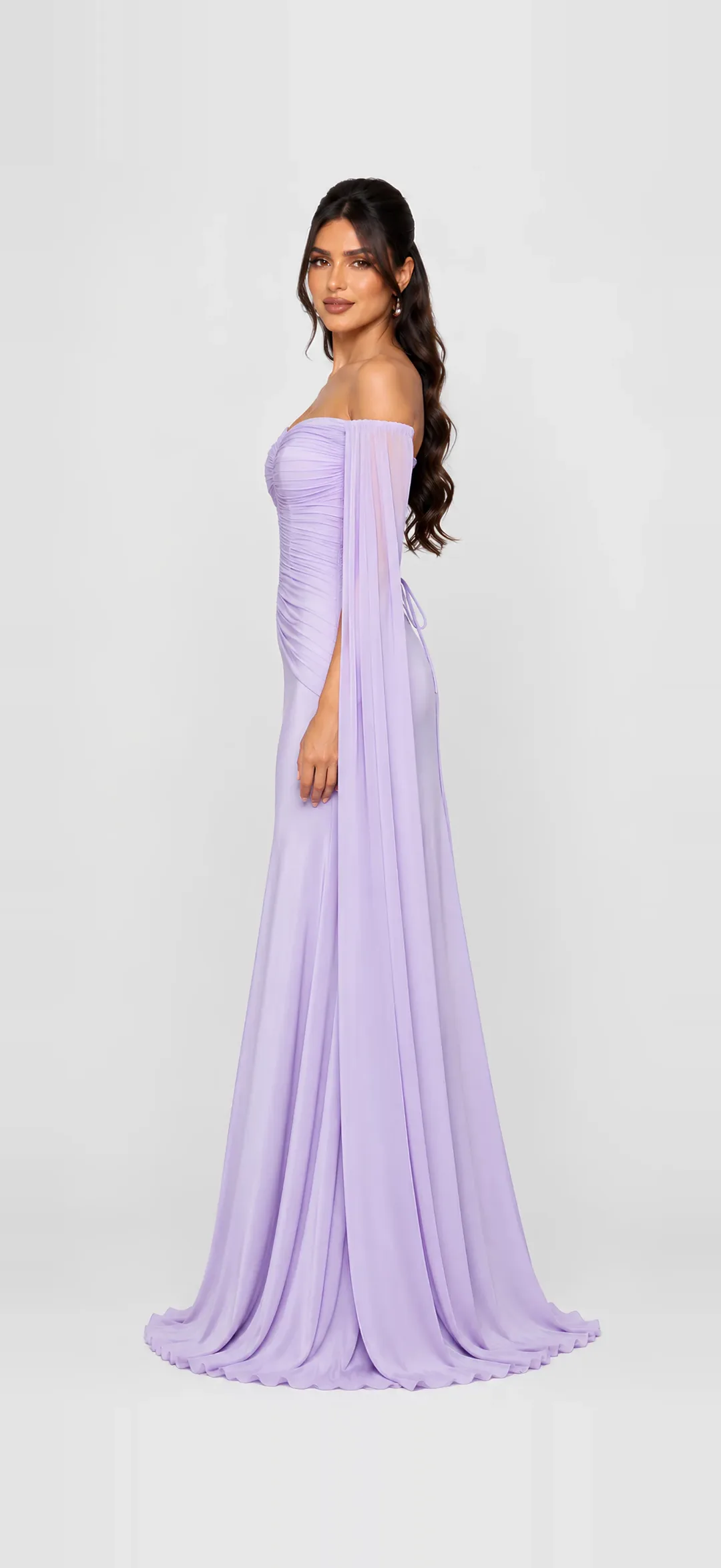 A Joie Couture lilac off-shoulder draped gown with sheer cape sleeves, photographed full length on a soft grey studio backdrop